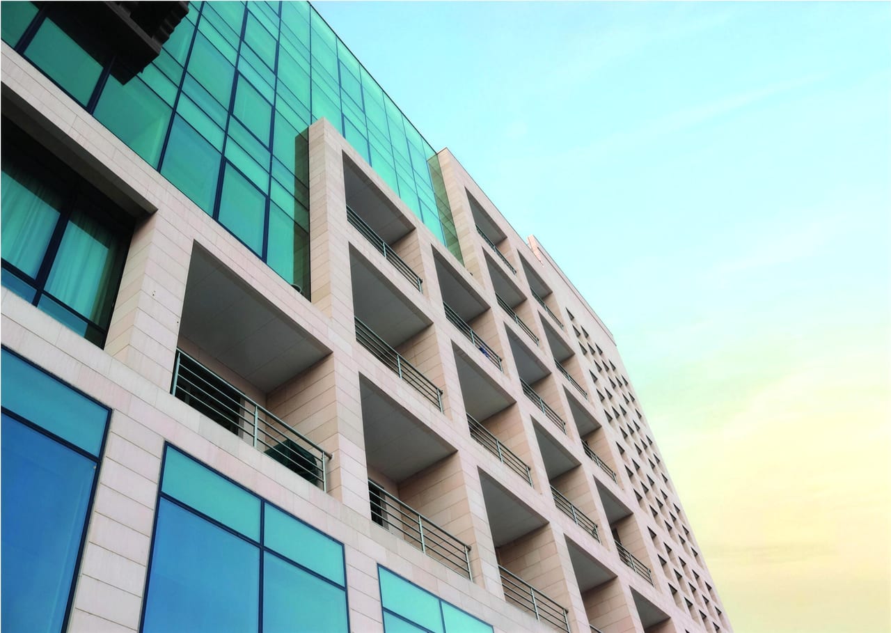 Upward view of the façade showing stone frames, glass panels and balconies