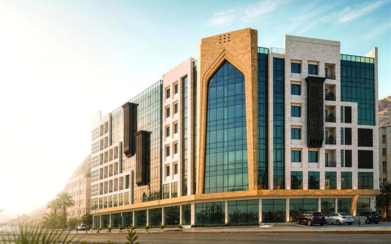 Al Rawdah Building in Bousher: stone and glass façade with an arched glass entrance